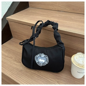 Detail shot of black nylon shoulder bag with lace heart bunny patch on wooden stairs