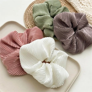 Close-up of pleated satin scrunchies in pastel pink, white, green and purple colors