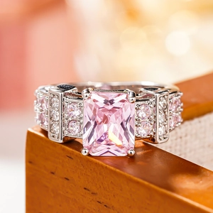 Macro shot of a rectangular pink gemstone ring with side stones on a wooden jewelry box