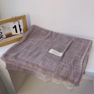 Detailed view of folded cotton linen scarf with soft fringe edge and studio brand label