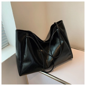 Close-up of the glossy black faux leather texture on a minimalist large tote bag