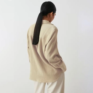 Detail of loose beige long-sleeved cotton crepe shirt showing fabric texture and back view
