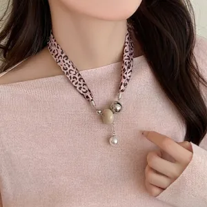 Detail of pink leopard print ribbon necklace with pearl pendants on model's neckline