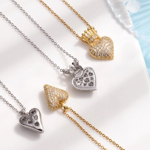 Gold and silver heart necklaces with crown detail and zircon pavé on white stone plate