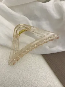 Detail shot of a triangular amber hair claw clip with golden metal spring on fabric