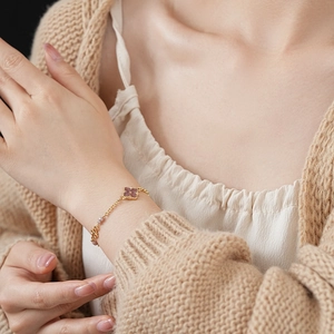Detail of vintage gold bracelet with purple clover stone on model's wrist