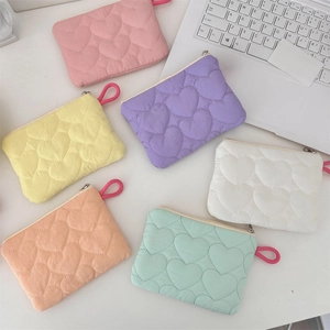 Close-up of heart-quilted candy-colored pouches in six pastel colors on a bright desk