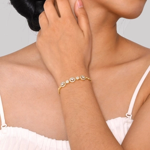 Makroaufnahme eines vergoldeten Armbands mit runden Zirkonia-Gliedern am Handgelenk