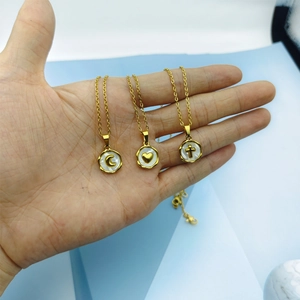 Close-up of golden necklaces featuring shell inlays with moon, heart, and cross charms
