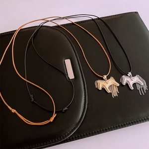 Close-up of gold and silver horse pendants with tassels on leather background