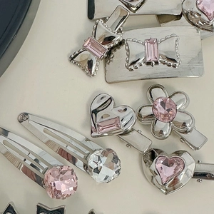 Macro detail of pink rhinestone hair clips with silver alloy bases in floral shapes