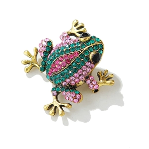 Gros plan d'une broche grenouille vintage avec strass verts et roses sur métal doré