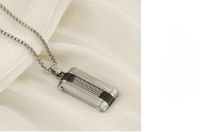 Detailed macro of a rectangular pendant necklace featuring silver steel cable texture