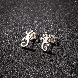 Vue macro de boucles d'oreilles gecko en acier inoxydable sur un fond noir texturé élégant