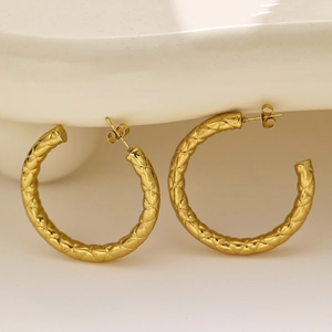 Detail view of gold hollow hoop earrings with textured quilted metal surface