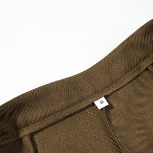 Λεπτομερής κοντινή λήψη υφής twill σε σκούρο χακί και ετικέτα μεγέθους S στο παντελόνι
