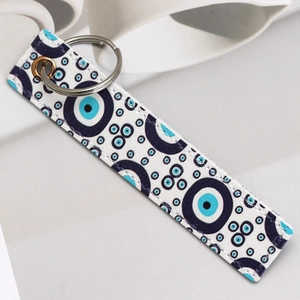 Close-up of rectangular faux leather keychain featuring a blue evil eye pattern and ring