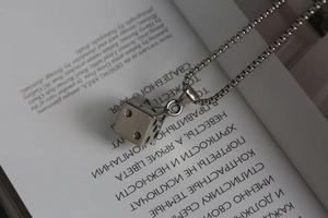 Macro shot of a silver steel dice pendant with star carving resting on an open book