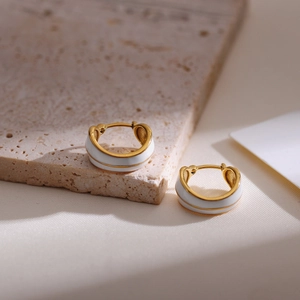 Macro shot of gold-plated hoop earrings with white enamel on a stone display
