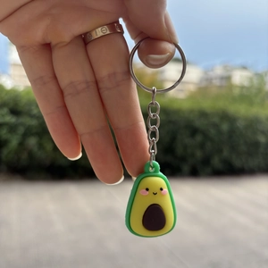 Close-up of a cute cartoon avocado keychain with a smiling face and metal ring