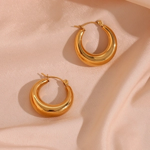 Polished 18K gold plated 25mm hollow hoop earrings on soft pink silk fabric background