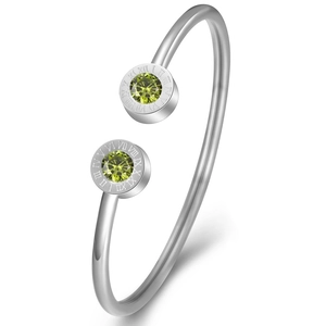 Macro shot of silver stainless steel bangle with Roman numerals and green zircon