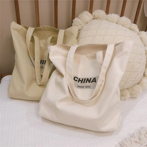 Gros plan de sacs cabas en toile avec texte China posés sur une parure de lit