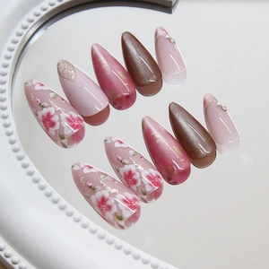 Cat eye almond press-on nails with peach blossom design and pearl accents on mirror