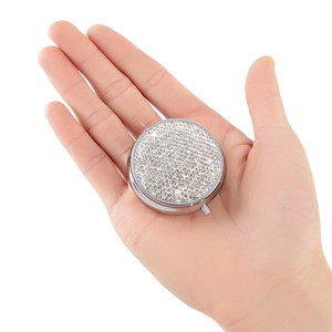 Close-up of a silver rhinestone pill box held in hand to show its portable mini size