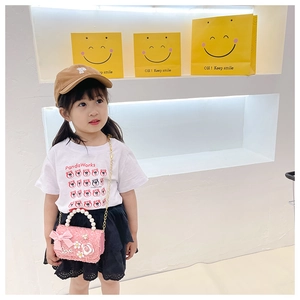 Pink tweed crossbody bag featuring pearl handle and bow detail worn by child model