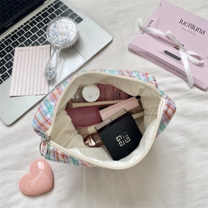 Flat lay of colorful checkered makeup bag filled with cosmetics and skincare tools