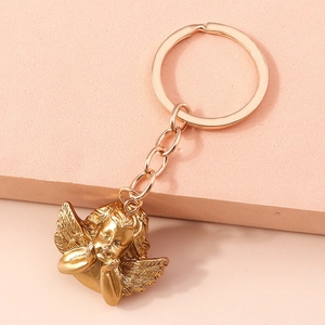 Detail view of retro matte gold angel pendant keychain on a soft pink background