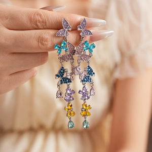 Macro view of crystal-encrusted butterfly and floral tassel earrings with colorful rhinestones