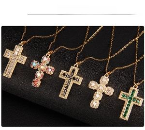 Detail showing five gold-plated cross necklaces with multicolored zircon pavé on black background