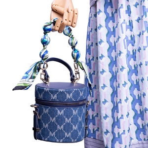 Blue denim cylinder bag with white M-pattern and colorful silk scarf handle wrap