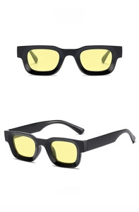 Close-up of retro square sunglasses featuring thick black frames and yellow tinted lenses