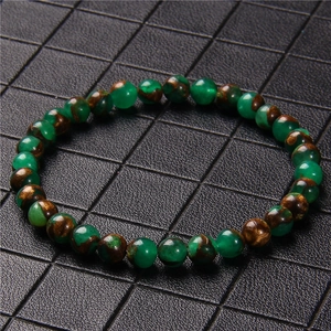 Macro shot of 6mm natural stone beads bracelet with gold powder on black textured background