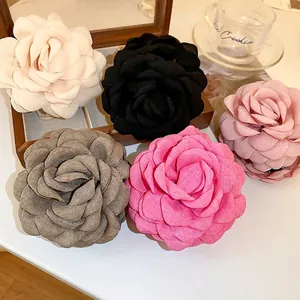 Elegant fabric camellia flower hair clips in five colors on a refined wooden tray
