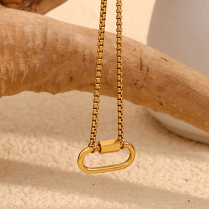 Close-up of gold 18K plated stainless steel oval carabiner pendant on textured wood
