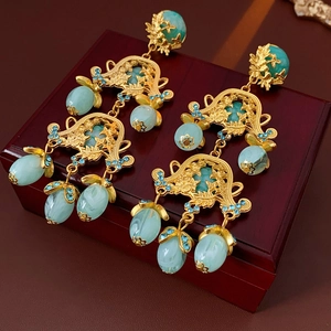 Macro shot of vintage gold flower hollow earrings with turquoise beads on a red wood box