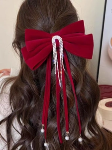 Dettaglio fiocco in velluto rosso con nappe di cristallo e perle su capelli castani