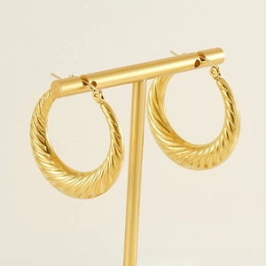 Macro shot of 18K gold plated twisted hoop earring displayed on a metal jewelry stand