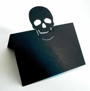 Detail of laser-cut black skull place card for Halloween featuring hollow design