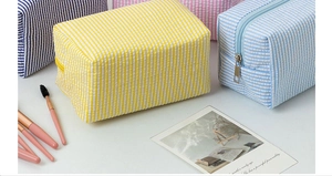Detail of seersucker makeup bags with colorful stripes and secure metal zippers