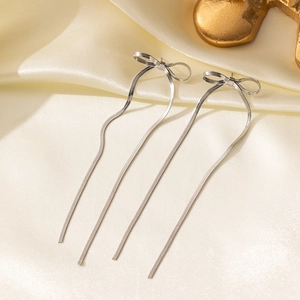 Detail of silver long tassel bow earrings with flat snake chains on silk fabric