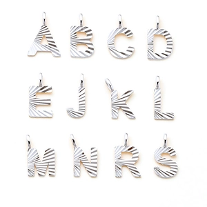Close-up of polished stainless steel letter pendants with unique radial engraved textures