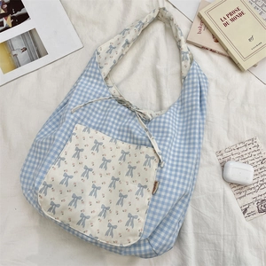 Détail du sac cabas en toile à carreaux bleus avec imprimé nœud floral et cordon de serrage