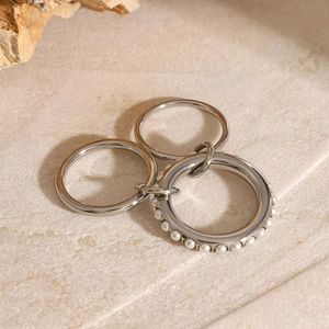Detailed view of silver multi-layered stainless steel ring set with white faux pearls