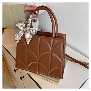 Close-up of brown quilted leather tote bag with a decorative silk scarf on the handle