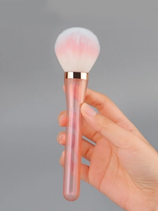 Close-up of fluffy pink gradient powder brush with rose gold ferrule and glitter handle